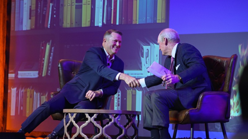 Two speakers shaking hands on a conference stage