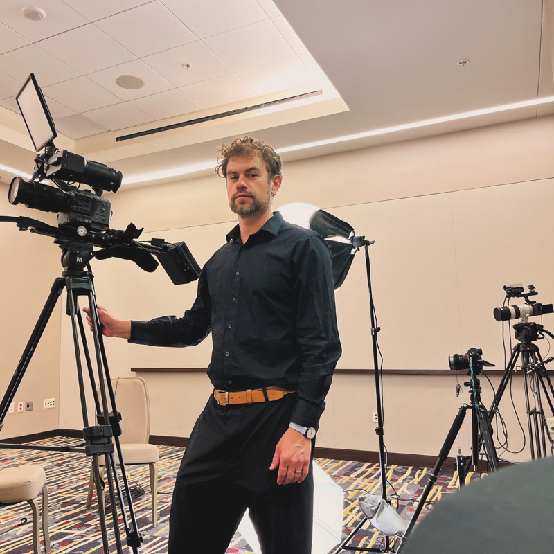 Dave Haft setting up three cameras for an interview in a conference room
